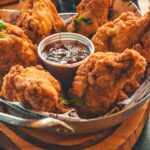 A tray with fried chicken and a small cup of ketchup sauce